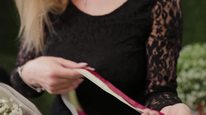 职业女性花店解开红丝带，用剪刀剪开以包装花束