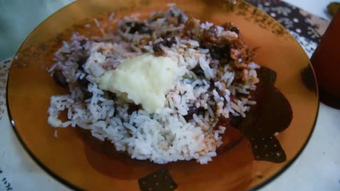 巴西老年妇女吃豆和米饭配鸡肉。在盘子上特写。