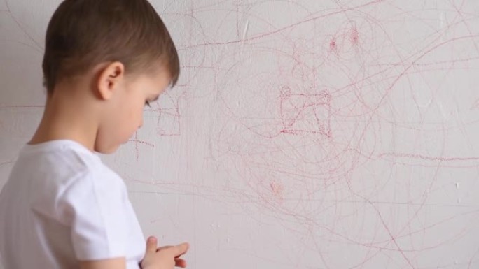 男孩用彩色粉笔在墙上画画。孩子在家从事创造力