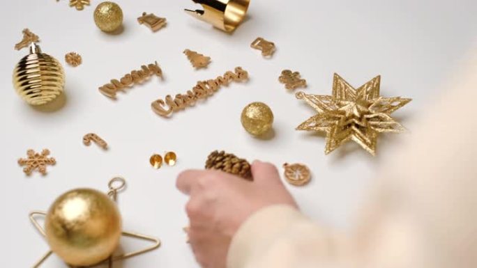 女人手工装饰金色圣诞物品在桌子上的圣诞树形状