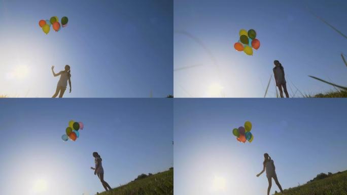 一个女孩在蓝天上玩彩色气球，慢动作