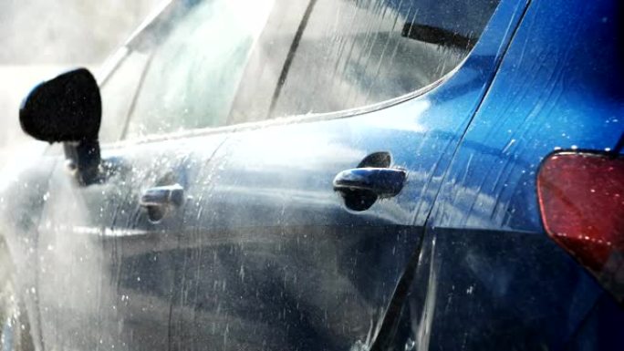 蓝色汽车在闪亮的日子里用喷水水洗手