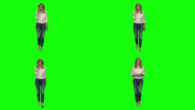 金发女子在绿屏上平静地在手机上行走和交谈。色度键，4k镜头。前视图