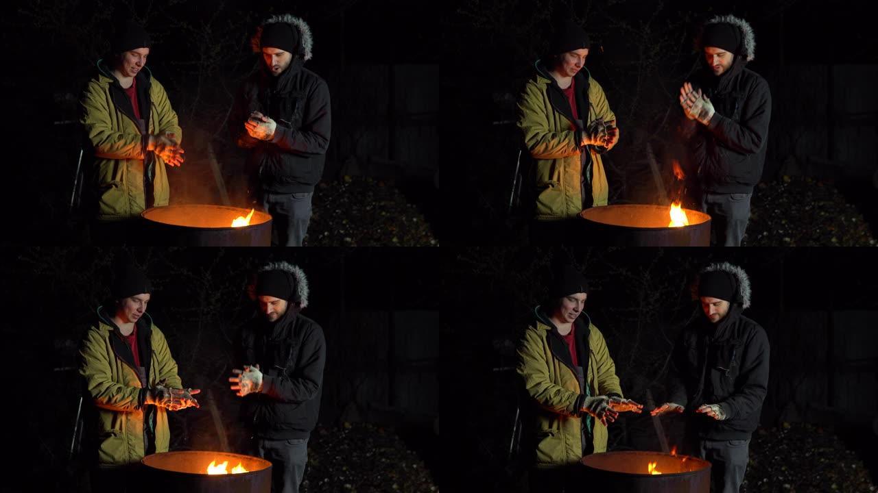 两个无家可归的年轻人在火中晒太阳。晚上，人们站在一桶火附近。