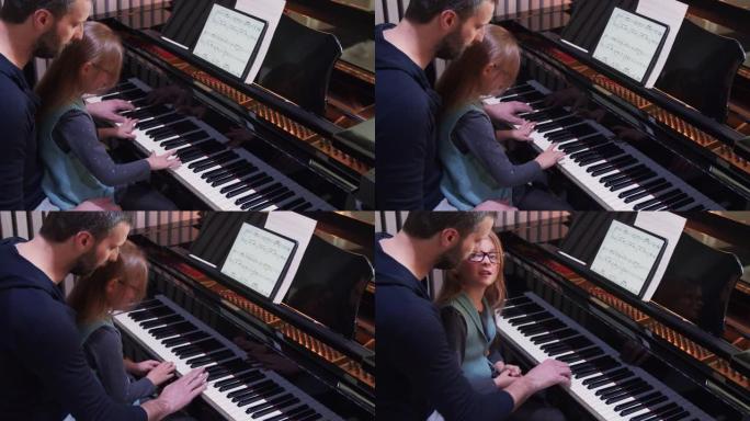 爸爸给女儿教钢琴。小女孩在家学钢琴。俯视图。在家的钢琴课。从父亲那里学习钢琴的孩子