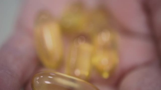 黄色胶囊omega-3脂肪酸倒入女性手掌，健康饮食和免疫系统增强概念，极端特写