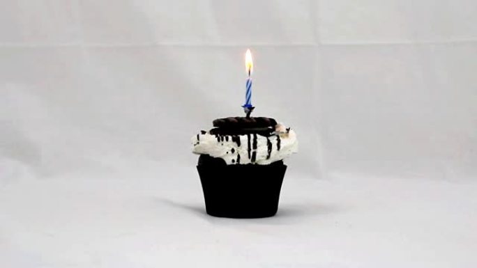 带有饼干和顶部点燃的蓝色蜡烛的纸杯蛋糕被炸掉了
