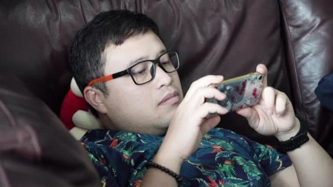 亚洲人在家中使用智能手机在线玩游戏。