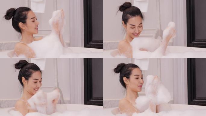 美丽的亚洲女人在浴室泡泡浴。洗澡时，她带着快乐的情绪喝着酒。