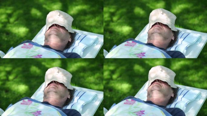 老人在外面被帽子遮住打盹。退休老人睡在树下