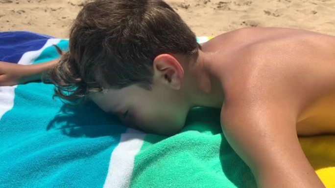 小男孩躺在海滩上休息