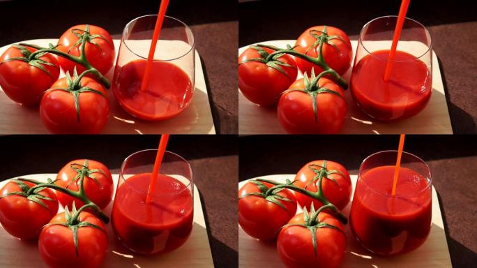 美味的番茄汁与成熟的红色西红柿玻璃杯。将番茄汁倒入玻璃杯中