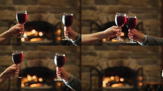 在燃烧的壁炉的背景上碰碰眼镜。4k慢动作视频