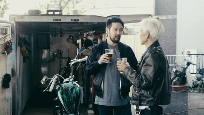 父子俩在摩托车车库前喝啤酒