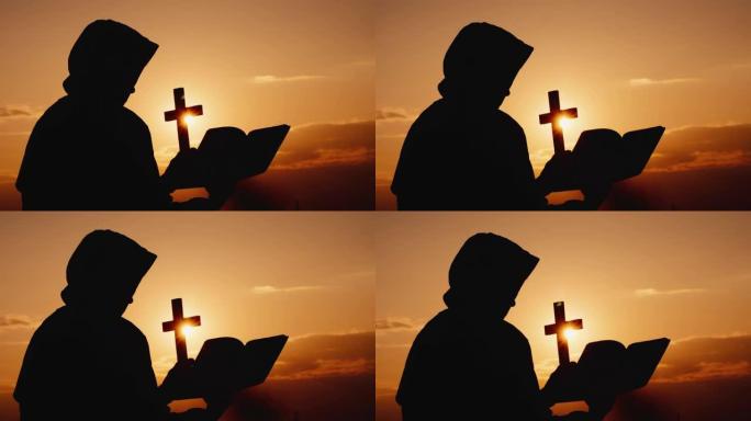 一位蒙头的和尚手里拿着耶稣受难像，站在日落时戏剧性的天空的背景下