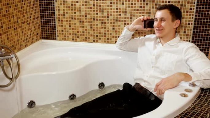 穿着裤子和衬衫的男人躺在水浴中，在电话中交谈