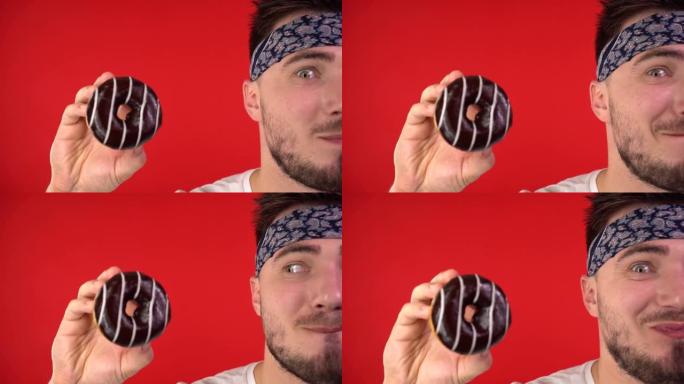 一个黑发男人的特写镜头。一个男人手里拿着一个釉面甜甜圈，一个男人忍不住想咬一个甜甜圈。爱吃甜食的人，