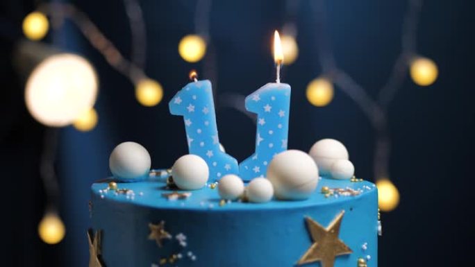 11号生日蛋糕星星天空和月亮概念，蓝色蜡烛被打火机点燃，然后吹灭。如果需要，请在屏幕右侧复制空间。特
