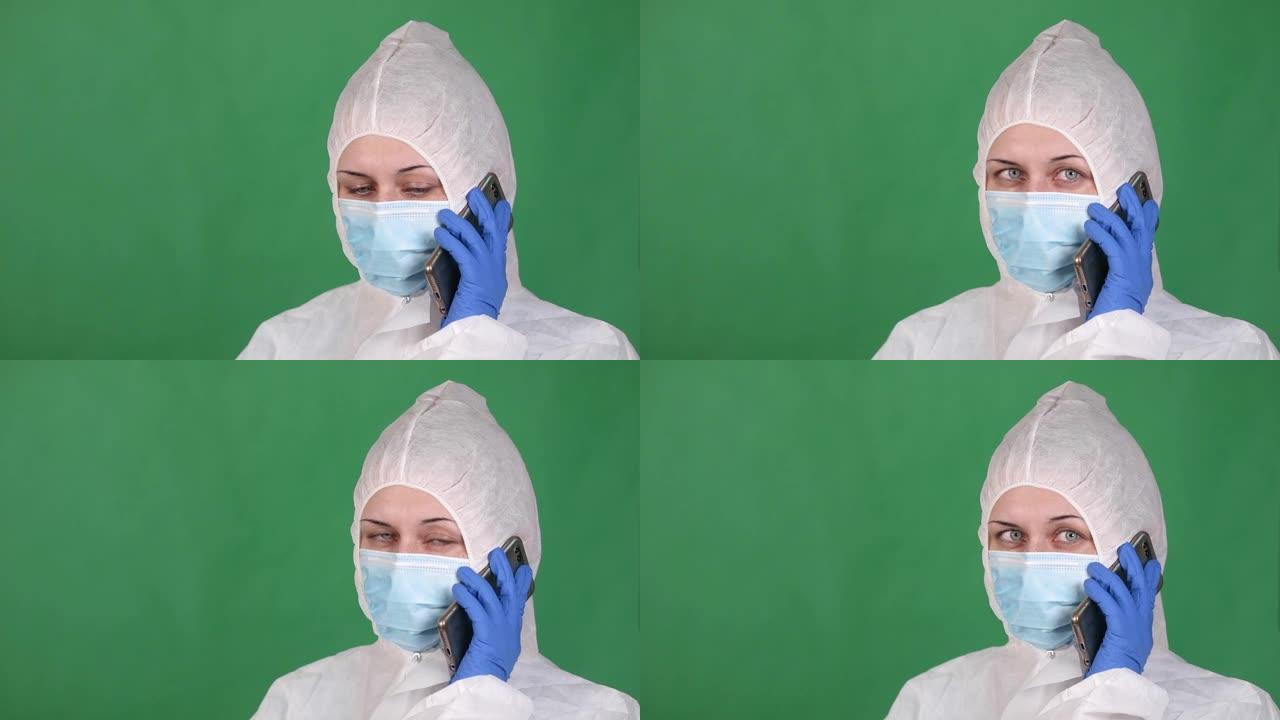 年轻的女军医穿着白色雾蒙蒙的外套在电话上讲话，戴着防护口罩，绿色背景上戴着橡胶手套