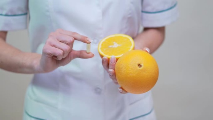 营养师医生健康生活理念-持有维生素药丸和橙色水果