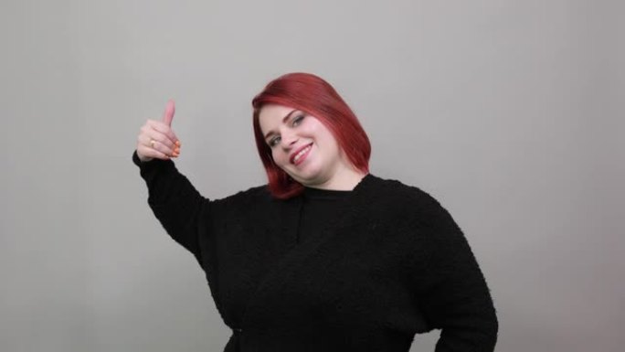 穿着黑色毛衣的年轻红发胖女人快乐的女人竖起大拇指