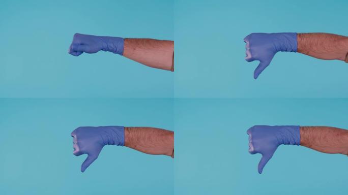 蓝色手术乳胶手套的男性手显示拇指向下孤立在蓝色背景