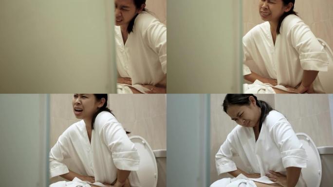 年轻的亚洲妇女在家里的马桶上便秘。医疗保健概念。