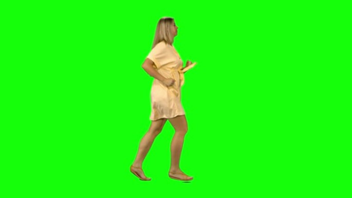 晒黑的金发女人在绿色屏幕上微笑着奔跑。纵断面视图