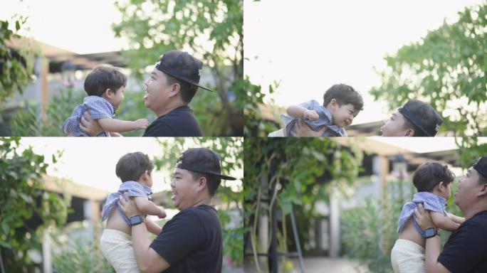 亚洲父亲在假期中亲吻和举起可爱的蹒跚学步的男孩