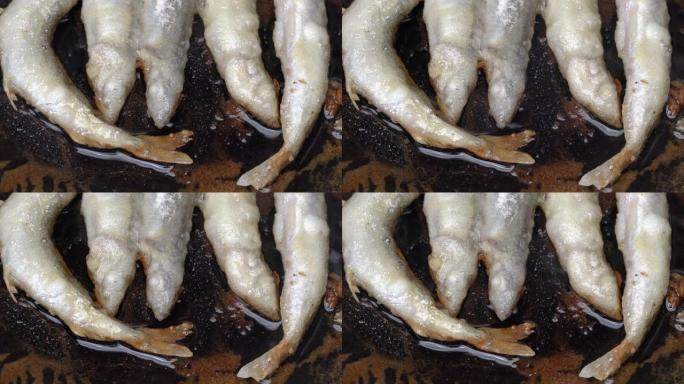 在铁锅中烹饪炸毛鳞鱼的特写视图。烤卡普林鱼 -- 亚洲美食，从头到尾，鱼子和骨头