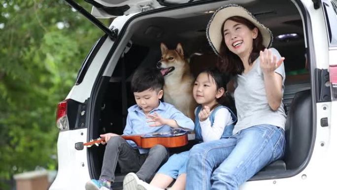 宠物爱好者。一个亚洲家庭，有一个母亲，女儿和儿子，在一辆面包车上看着海边的景色。快乐的亚洲儿童和母亲