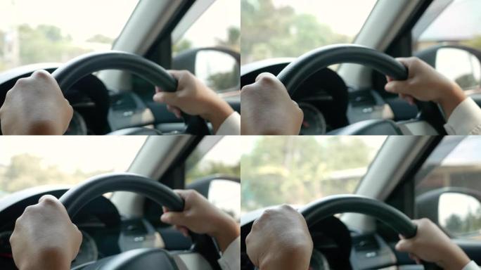 小心驾驶汽车时，女性手在黑色方向盘上的特写。