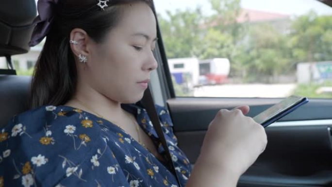 年轻女性亚洲人的场景她坐着放松，在汽车上使用智能手机搜索网站，女性使用智能手机的概念