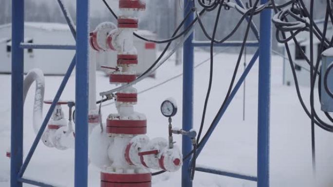 冬季在油田用钻机工作和泵送化石燃料能源用原油的工业石油电动离心泵。井口连接油井的设备。