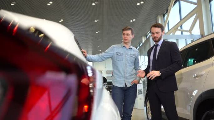 高加索专业汽车推销员和年轻客户讨论新车。