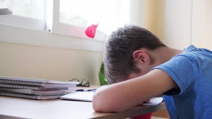 孩子累了做作业，男孩把头放在手上，不想学习