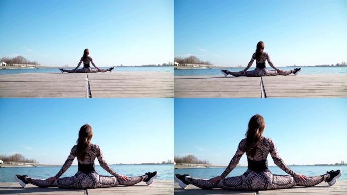 运动苗条的年轻女孩坐在美丽的蓝湖的背景上。户外瑜伽课。慢动作。在斯蒂安卡姆射击。