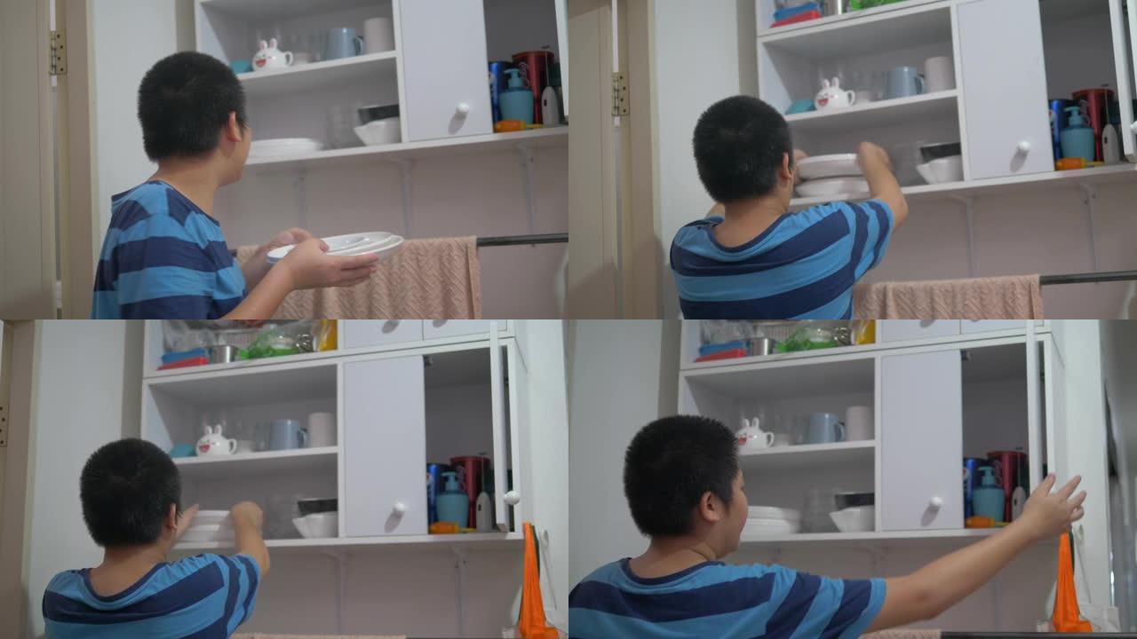 亚洲青春期男孩拿着白色盘子，放在架子橱柜上。