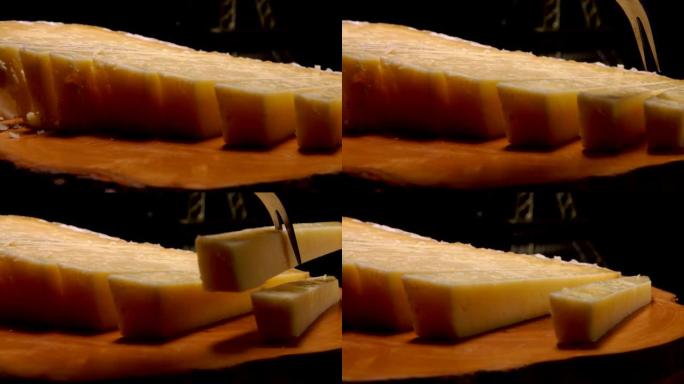 叉子从木板上拿了一块法国硬奶酪