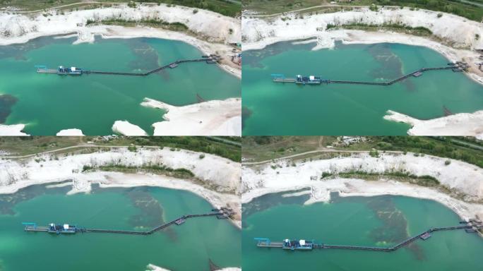 视频，无人机从飞行穿过一个采石场池塘，将雪白的石英砂带到池塘中间的吸水挖泥船，该挖泥船与传送带相连。