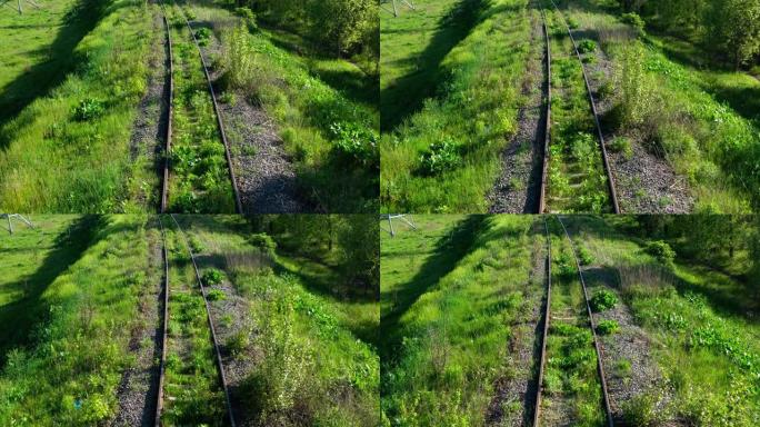 铁轨。鸟瞰图。林区绿树成荫的草地之间的铁路。运输和旅行