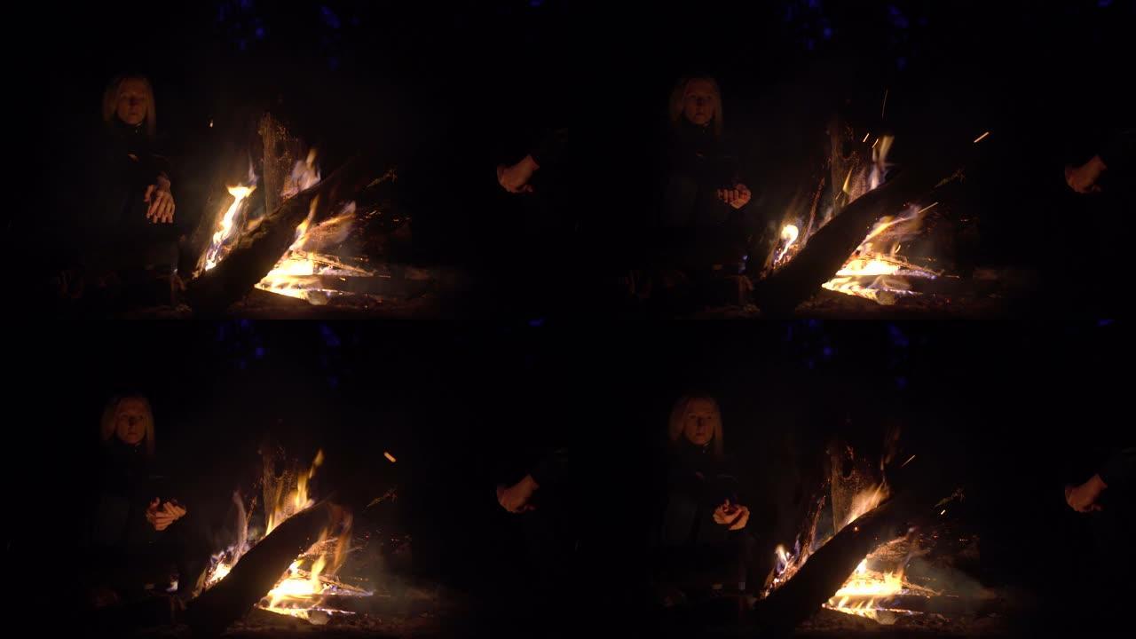 朋友们晚上坐在火炉旁。周围的人篝火，沐浴在火中，放松概念，篝火，放松，希望，人性，自然，游客。