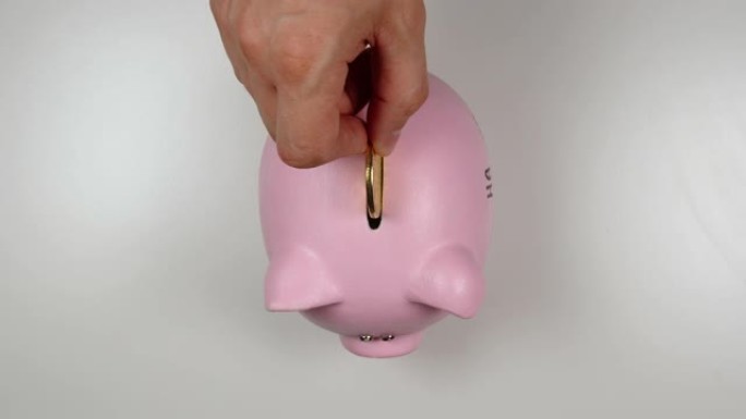 俯视图: 手将硬币扔进粉红猪钱箱