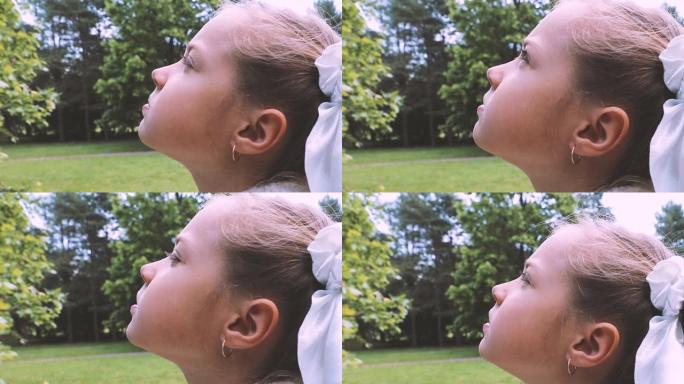 体贴的小女孩满怀希望地仰望天空的特写镜头。