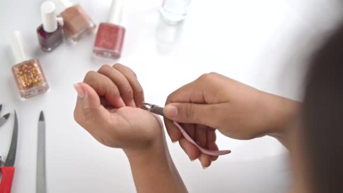 美丽的亚洲女人自己美容指甲，用小剪刀剪，修指甲和绘画，新型冠状病毒肺炎涂抹时在家用丙酮清洁油漆。