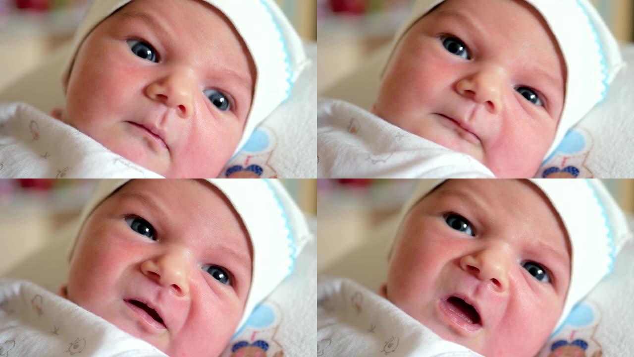 蓝眼睛的新生婴儿移动了他的嘴，看着相机。照顾儿童的概念。首先看世界。可爱的孩子不明白他周围发生了什么