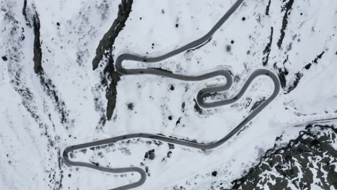 意大利多洛米蒂山脉扭曲道路的鸟瞰图，在白雪覆盖的山丘中蜿蜒曲折，是滑雪者和车迷中了解跑车的著名场所，