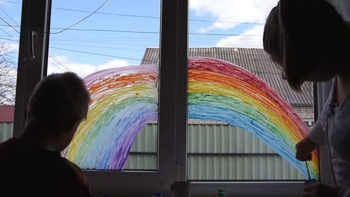 女孩和男孩在家里新型冠状病毒肺炎检疫时在窗户上画彩虹。居家社交媒体预防冠状病毒运动