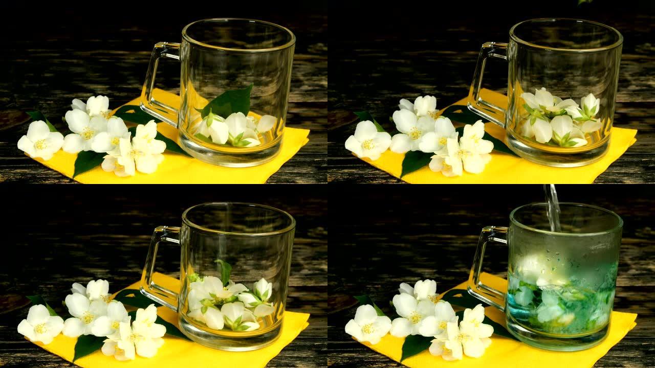 准备茉莉花茶。将新鲜的茉莉花花瓣和花朵扔进玻璃透明茶杯中，并用开水倒入。