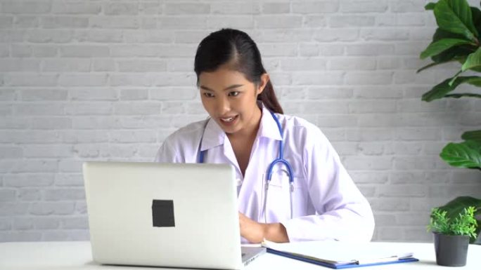 在线视频会议与亚洲女医生和病人聊天，同时在笔记本电脑上讨论和诊断，看着相机
